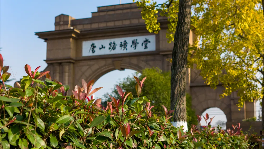 树叶掩映下，写有唐山路矿学堂的西南交通大学校门