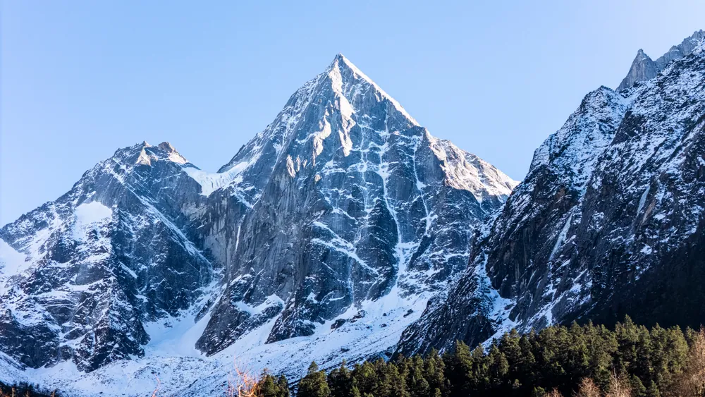 蓝天下的四姑娘山幺妹峰，积雪覆盖陡峭的山脊